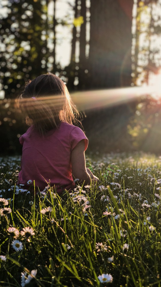 Child on Flowerbed at Sunrise